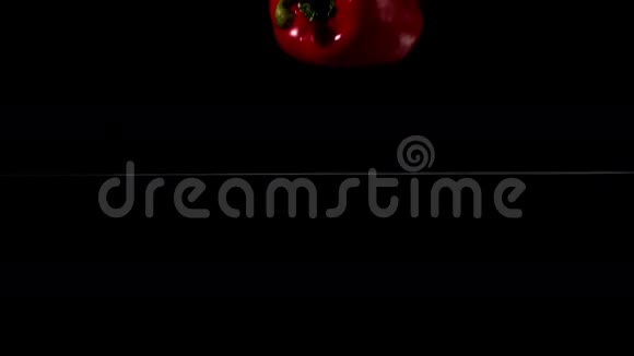 红辣椒落在黑色背景的水里视频的预览图