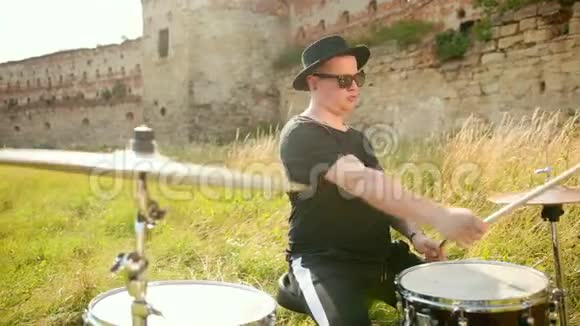 音乐家戴着黑帽子在街上演奏鼓组和视频的预览图