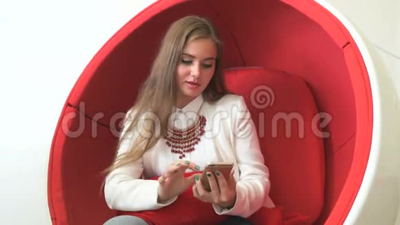 女客户坐在红色椅子上拿着智能手机视频的预览图