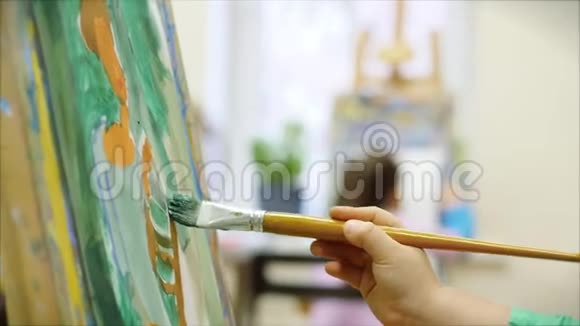 年轻的艺术家的手小女孩艺术家用画笔描绘画布坐在桌子上画画布程序视频的预览图