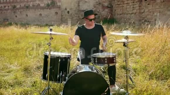 音乐家穿着黑色的衣服戴着帽子演奏鼓组和视频的预览图