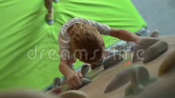 一个小男孩正在一个巨石攀爬体育馆里爬墙视频的预览图