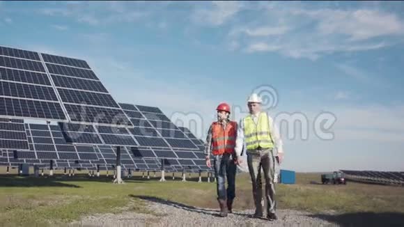 在一排排太阳能电池板之间行走的工人视频的预览图