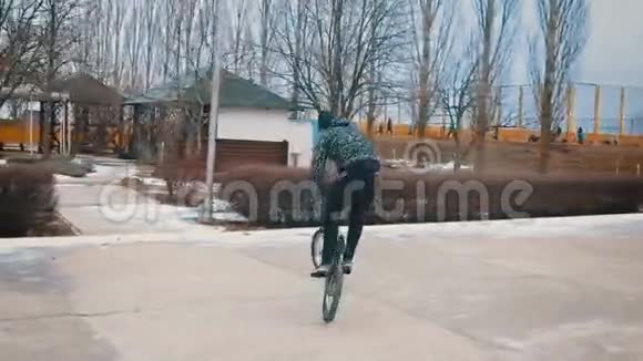 青少年骑着BMX在冬季公园慢动作做戏法120英尺视频的预览图