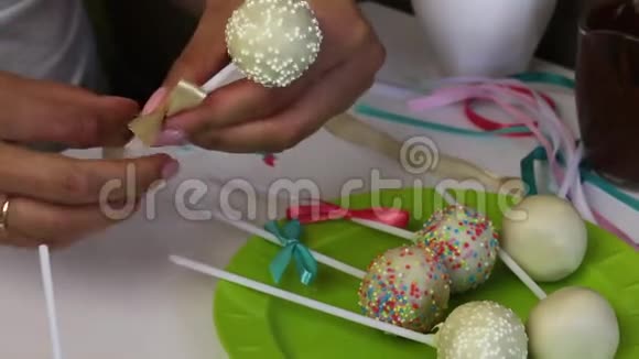 一个女人在盘子里装饰辫子蛋糕的蝴蝶结糖果装饰着调料视频的预览图