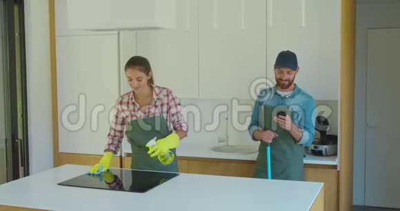 男人和女人作为一个单一形式的专业清洁工在厨房工作期间玩得很开心视频的预览图