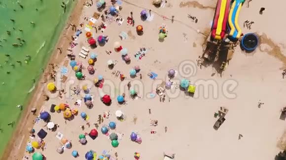 在阳光明媚的热天鸟瞰拥挤的海滩黄沙和雨伞视频的预览图