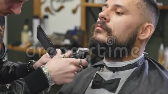 在现代理发店里一个身材矮小英俊留着胡须的年轻男子在理发视频的预览图