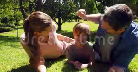小男孩和父母对着公园里的摄像机微笑视频的预览图