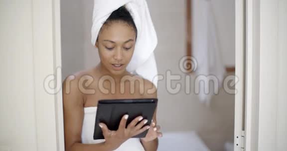 使用平板电脑穿浴巾的年轻女子视频的预览图