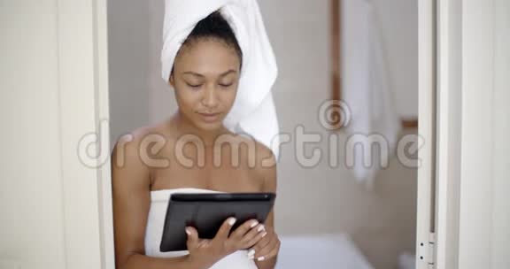 使用平板电脑穿浴巾的年轻女子视频的预览图