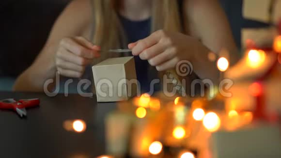 一个年轻的女人打包礼物现在用手工纸包裹上面有红色和金色的丝带供圣诞节或新年使用视频的预览图