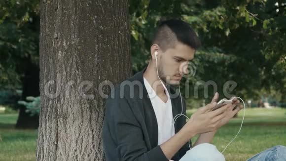 英俊的年轻人浏览智能手机视频的预览图