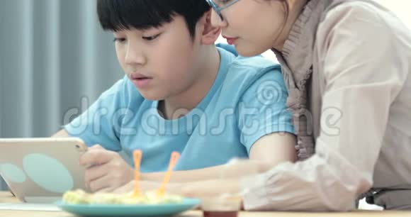年轻的亚洲母亲带着儿子一起在家看平板电脑玩平板电脑视频的预览图