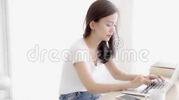 美丽的年轻自由职业亚洲女性微笑着工作在办公桌办公室配有专业电脑视频的预览图