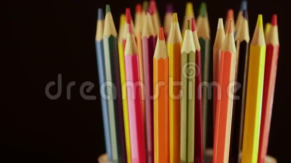 在玻璃的黑色背景上有多种颜色的铅笔明亮的彩色铅笔在玻璃杯中旋转视频的预览图