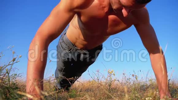 一个身体裸露的年轻运动员在大自然中做俯卧撑视频的预览图