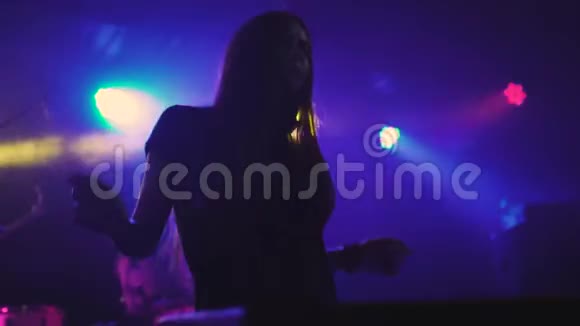 美丽的年轻女子DJ在夜总会的混合控制台播放音乐视频的预览图