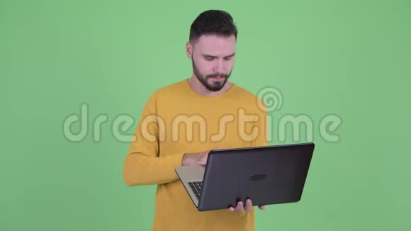 快乐的年轻英俊的胡须男在思考笔记本电脑视频的预览图