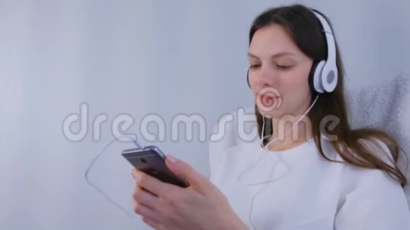 女人在智能手机上用耳机听音乐视频的预览图