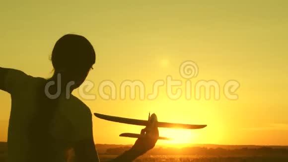 快乐的女孩带着玩具飞机在夕阳下的田野上奔跑孩子们玩玩具飞机少年梦想视频的预览图