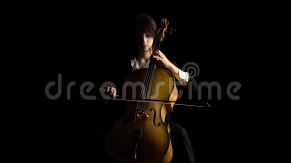 女孩在黑暗工作室演奏大提琴黑色背景视频的预览图
