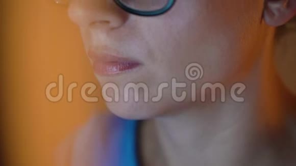 戴眼镜的女人看着显示器和上网监视器屏幕反映在眼镜上视频的预览图