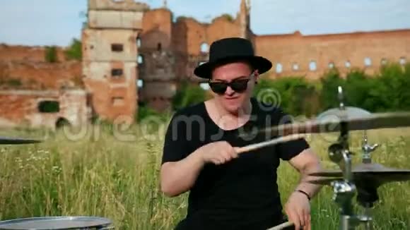 音乐家戴着黑帽子在街上演奏鼓组和视频的预览图