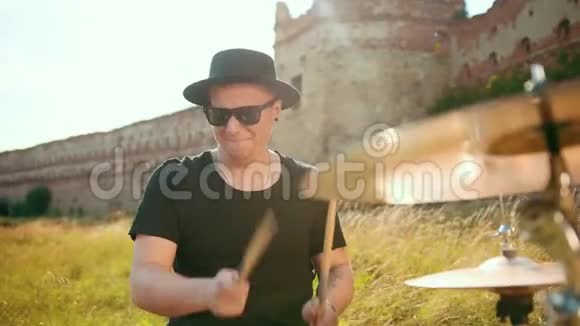 音乐家穿着黑色的衣服戴着帽子演奏鼓组和视频的预览图
