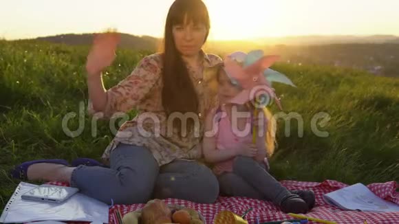 母亲和女儿在日落时在山上野餐视频的预览图