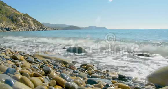 波浪降落在石滩上清澈的蓝色海水视频的预览图