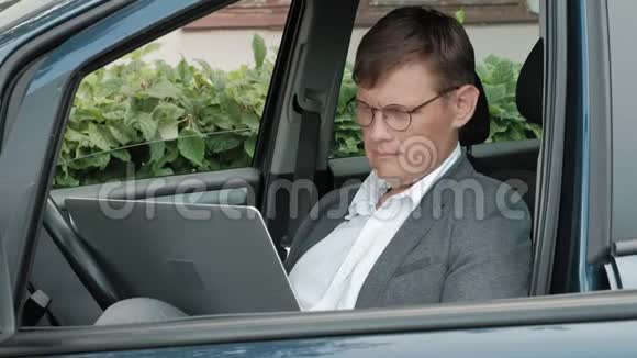 成熟的商人在车上工作手提电脑视频的预览图