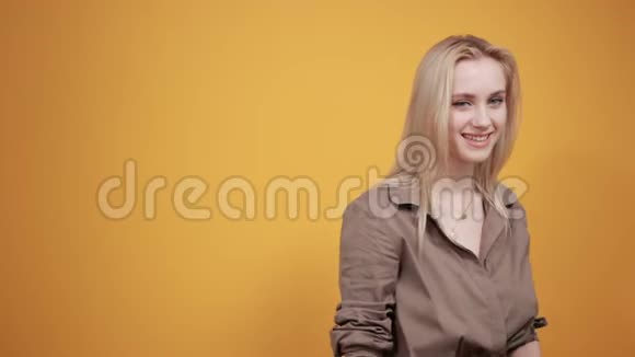 棕色上衣的金发女孩在橙色背景下表现出情感视频的预览图