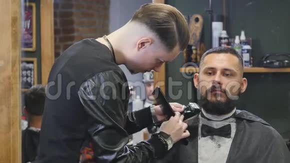 在现代理发店里一个身材矮小英俊留着胡须的年轻男子在理发视频的预览图