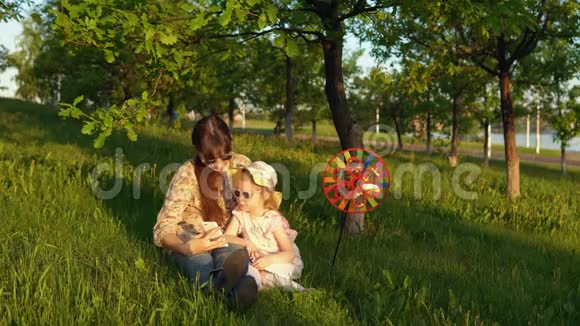 母亲和女儿在日落时快乐地一起在草地上玩耍视频的预览图