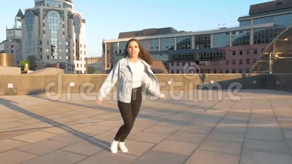 美丽的女孩长发在城市里跳舞夕阳的背景视频的预览图