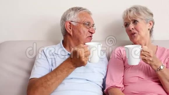 快乐的老夫妇在沙发上喝咖啡视频的预览图