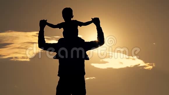 父亲和儿子在公园里玩耍夕阳下一个幸福的家庭剪影视频的预览图