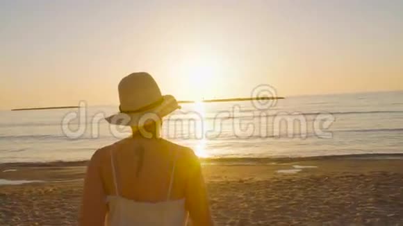 日落时分一位年轻的美女在海滩上散步视频的预览图