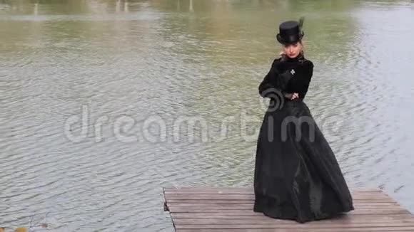 秋天在水的背景上穿黑色裙子的女孩视频的预览图