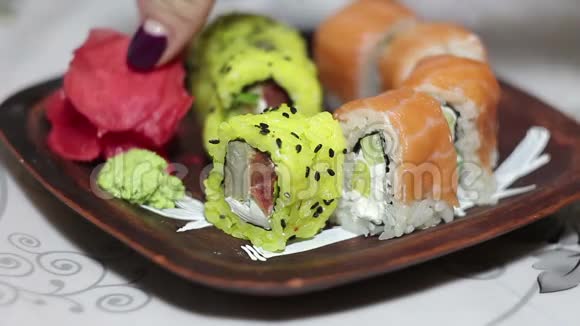 女性手拿腌制的生姜放在寿司卷上从盘子里拿出来视频的预览图