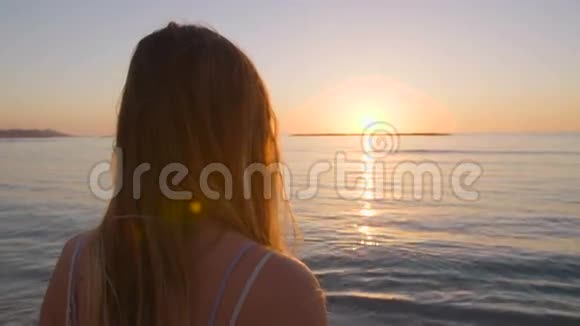 日落时分一位年轻的美女在海滩上散步视频的预览图