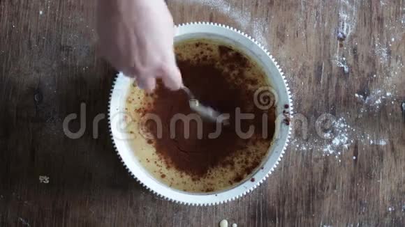 在白色塑料碗中用勺子搅拌巧克力饼干面团视频的预览图