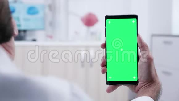 手持一部带有绿色屏幕模型的手机视频的预览图