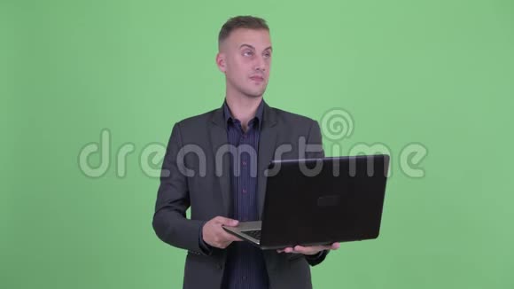 快乐英俊的商人在使用笔记本电脑时会思考问题视频的预览图