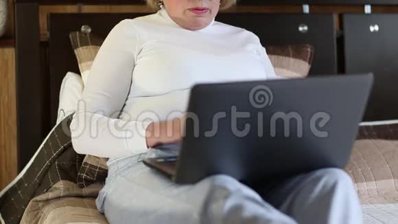 高级女性使用笔记本电脑键入文本视频的预览图