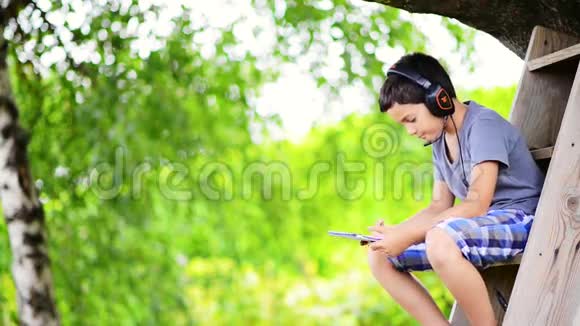 儿童听音乐用耳机在室外电脑上播放视频的预览图