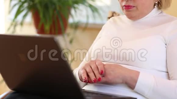 高级女性使用笔记本电脑键入文本带笔记本的女人视频的预览图