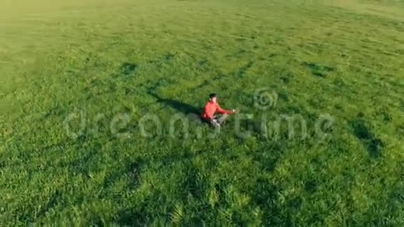 低空径向飞行超过运动瑜伽男子在完美的绿草在山上日落视频的预览图