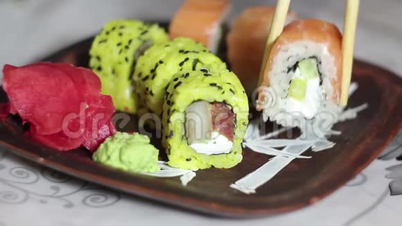 手拿筷子把寿司卷放在盘子里拿着生姜视频的预览图
